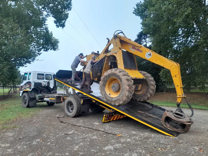 Peters Safety Kwik recovering a yellow industrial loader onto a flatbed truck